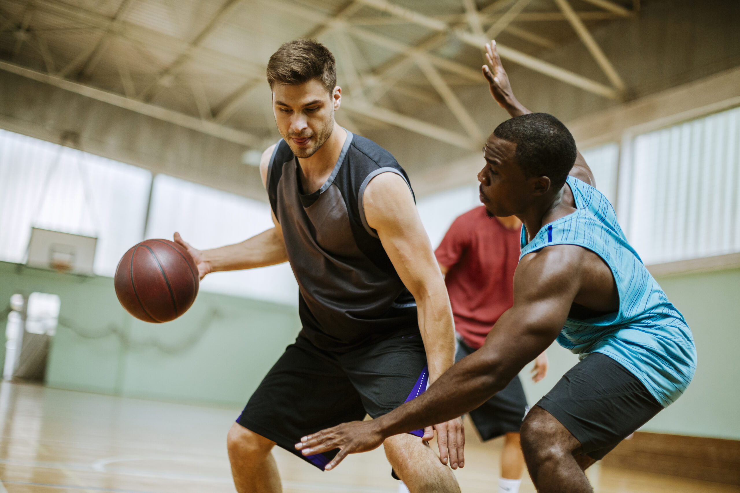 Two adult males, one wearing a black singlet and black shorts; the second player wearing a bright blue singlet and black shorts in basketball positions.