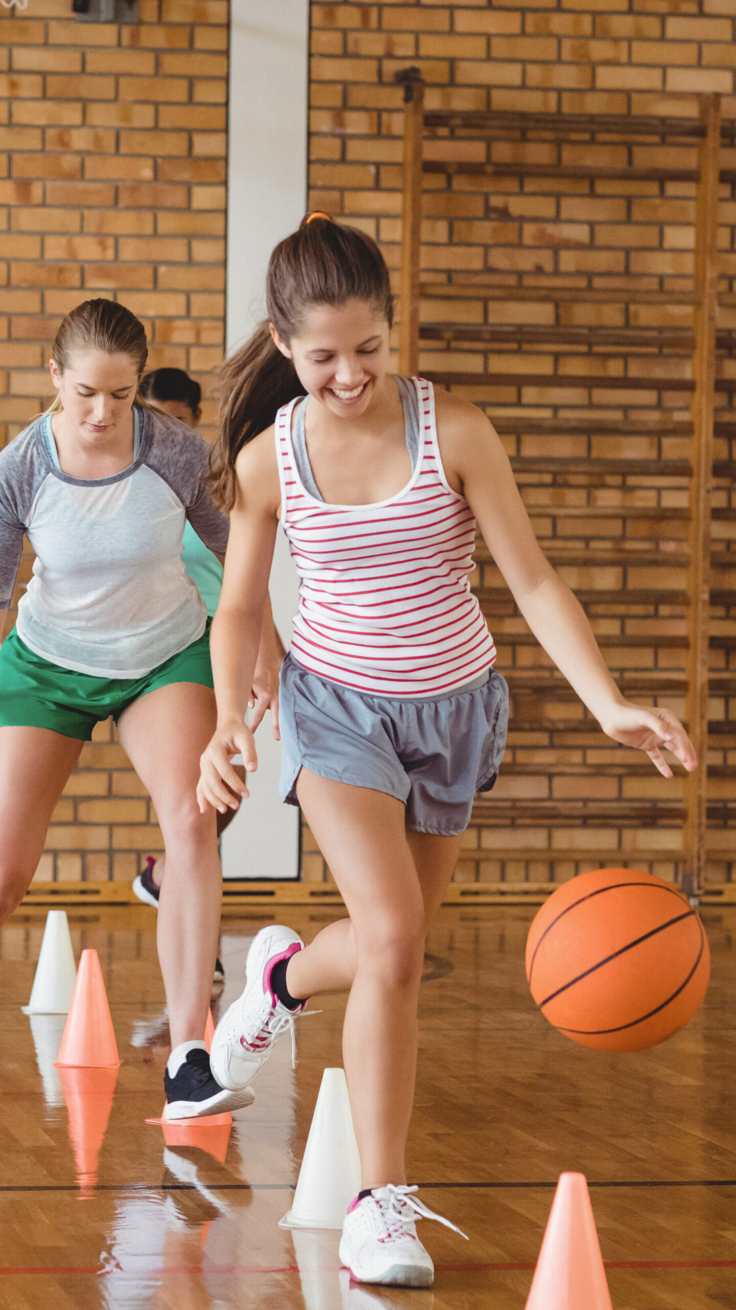 High school kids practicing football using cones for dribbling drill in the court